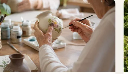 Mãos pintando um vaso de cerâmica em atividade de artesanato